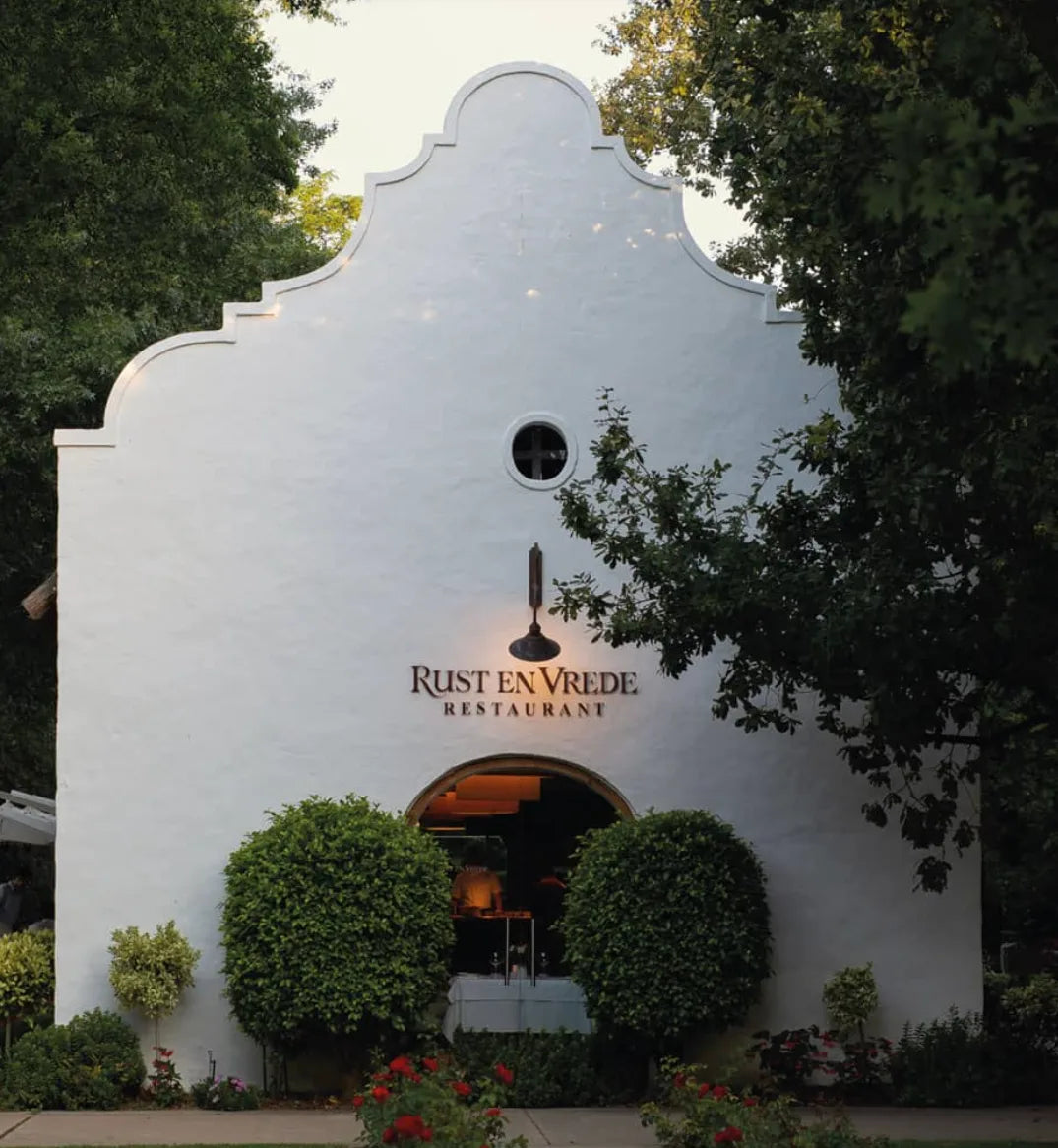 Weingut Rust-en-Vrede in Südafrika – kapholländische Architektur mit Weinbergen im Hintergrund