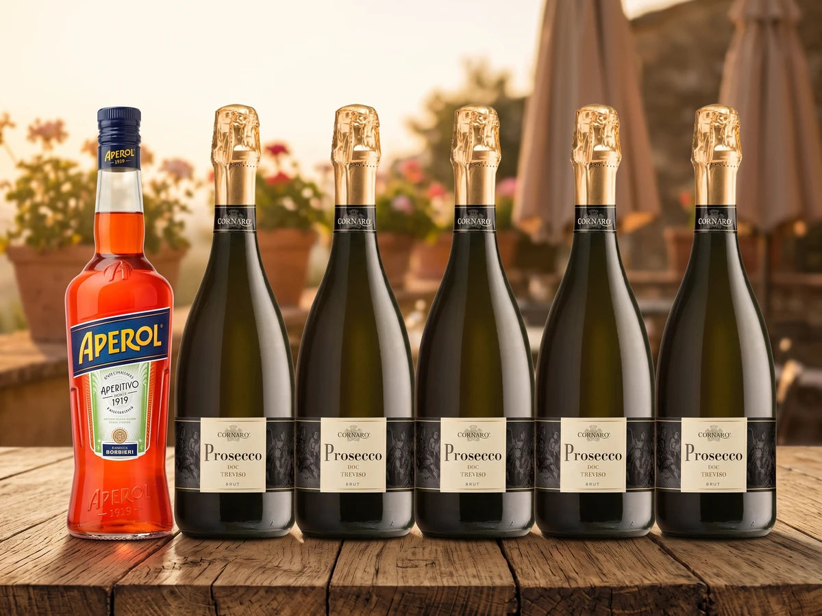 Aperol Spritz Paket Prosecco – eine Flasche Aperol und fünf Flaschen Cornaro Prosecco Treviso auf einem Holztisch vor sonniger Terrasse.