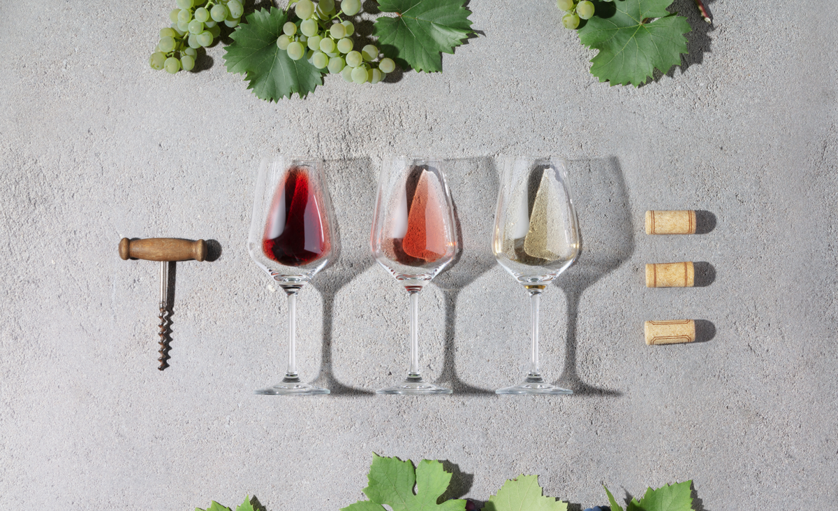 3 Weingläßer mit den drei Weinarten. Dazu Korken und Korkenzieher und Reben